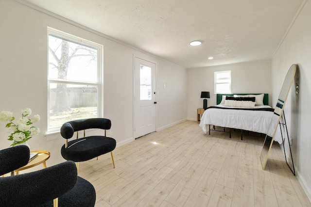 bedroom with light wood finished floors, a textured ceiling, baseboards, and ornamental molding