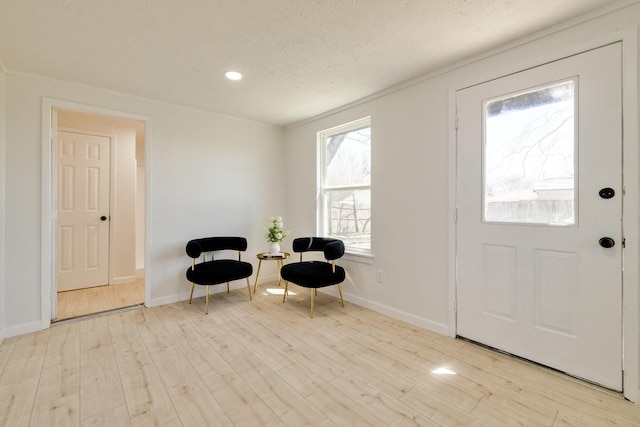 foyer entrance featuring baseboards, a textured ceiling, and wood finished floors
