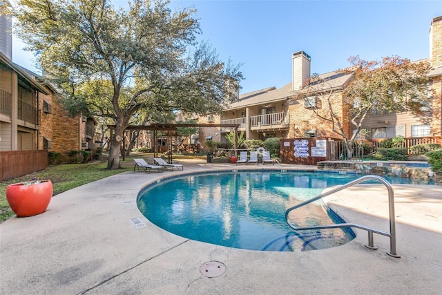 community pool with a patio area and fence