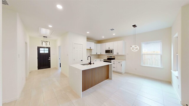 2227 Stoneman St, Dallas, TX 75215 - kitchen featuring stainless steel appliances, a sink, backsplash, a center island with sink, and light tile patterned floors