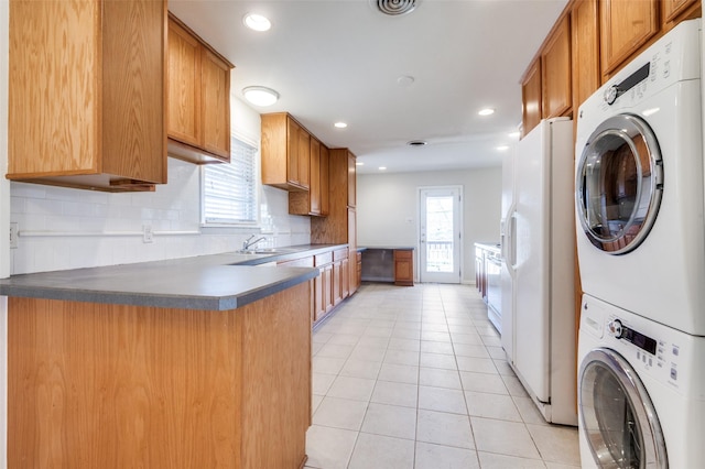 2645 Woodmere Dr, Dallas, TX 75233 - kitchen featuring light tile patterned floors, a peninsula, decorative backsplash, stacked washer and clothes dryer, and white fridge with ice dispenser