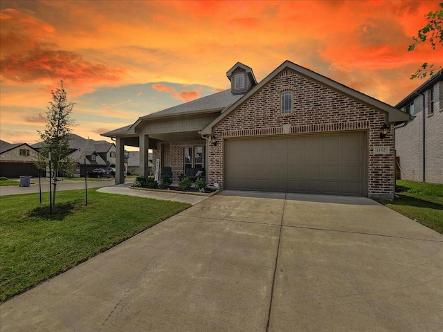 view of front of home with brick siding, a front lawn, a garage, and driveway