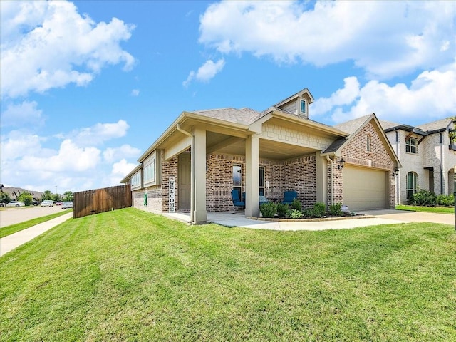 view of front of house featuring a front yard, fence, brick siding, an attached garage, and driveway