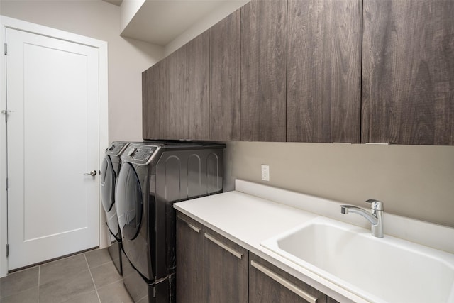 laundry room with cabinet space, light tile patterned floors, washer and clothes dryer, and a sink