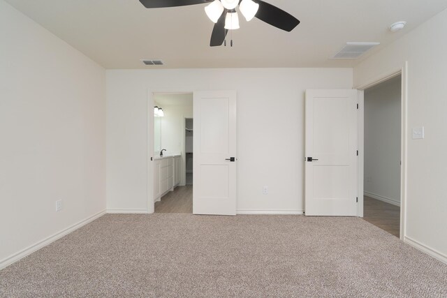 5557 N 10th, Abilene, TX 79601 - unfurnished bedroom with light colored carpet, baseboards, ceiling fan, and connected bathroom