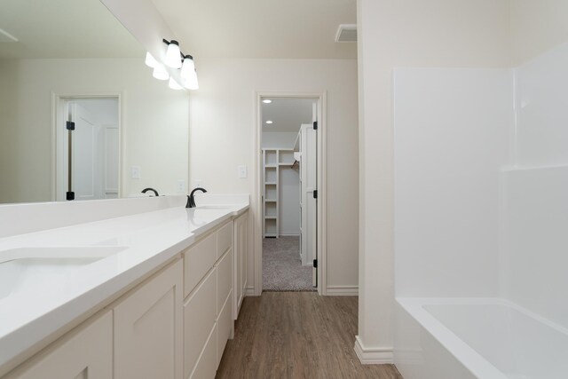5557 N 10th, Abilene, TX 79601 - bathroom with double vanity, wood finished floors, a spacious closet, baseboards, and shower / bath combination