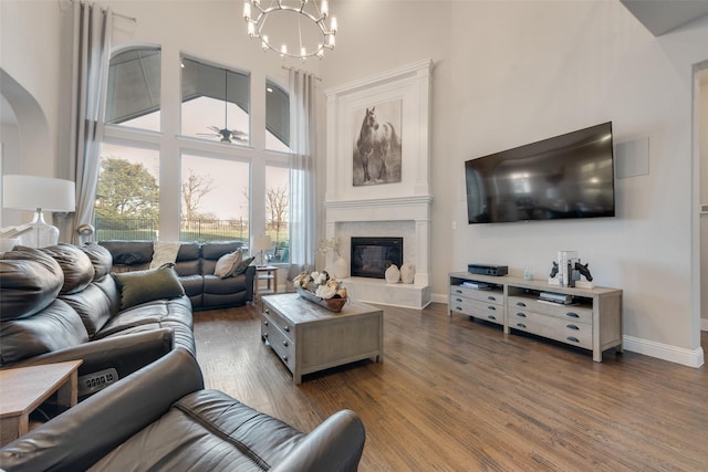 4406 Ravenbank Dr, Rockwall, TX 75087 - living area with a glass covered fireplace, wood finished floors, arched walkways, a high ceiling, and baseboards
