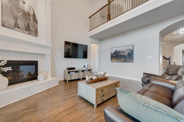 4406 Ravenbank Dr, Rockwall, TX 75087 - living room featuring baseboards, a fireplace, a high ceiling, wood finished floors, and arched walkways
