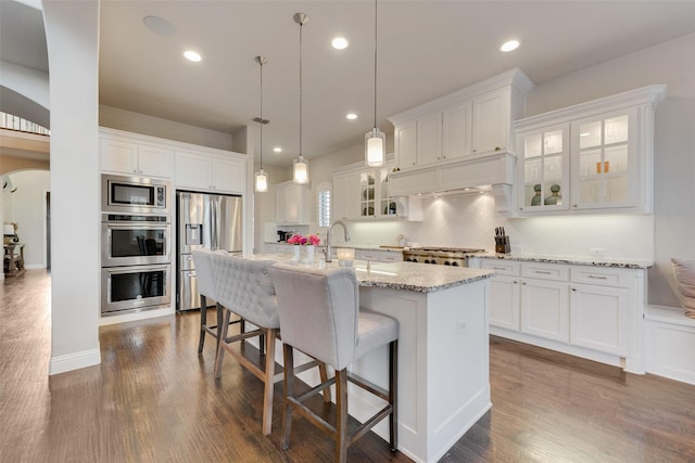 4406 Ravenbank Dr, Rockwall, TX 75087 - kitchen featuring arched walkways, white cabinets, stainless steel appliances, and custom exhaust hood