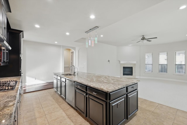 kitchen with a sink, arched walkways, appliances with stainless steel finishes, light tile patterned flooring, and ceiling fan