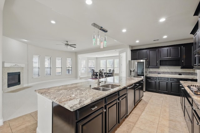 kitchen with light stone countertops, recessed lighting, a kitchen island with sink, ceiling fan, and a sink
