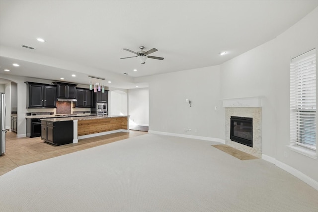 kitchen featuring visible vents, open floor plan, light carpet, and an island with sink
