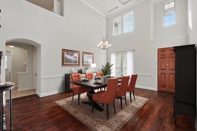 dining room featuring baseboards, arched walkways, plenty of natural light, and wood finished floors