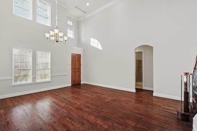 unfurnished living room featuring baseboards, arched walkways, dark wood-type flooring, and a chandelier