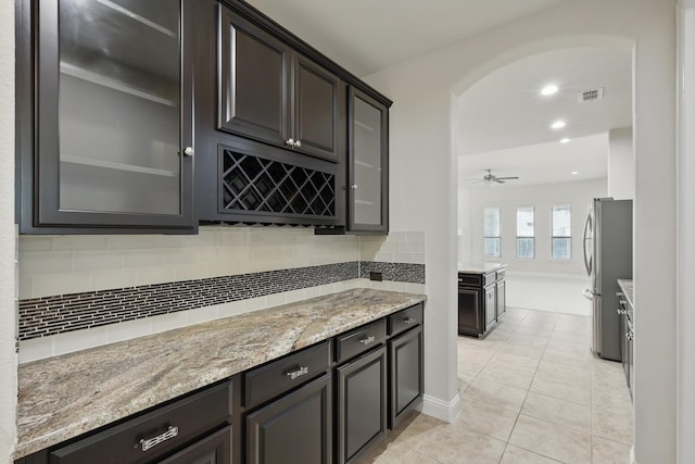 bar featuring backsplash, arched walkways, visible vents, and freestanding refrigerator