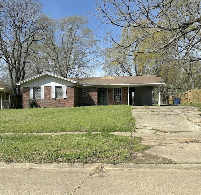 view of front of house with fence, concrete driveway, a front yard, a carport, and brick siding