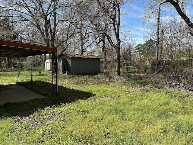 view of yard featuring fence, a carport, an outdoor structure, and a shed