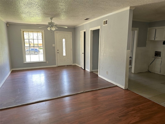 foyer entrance with visible vents, wood finished floors, a ceiling fan, and ornamental molding