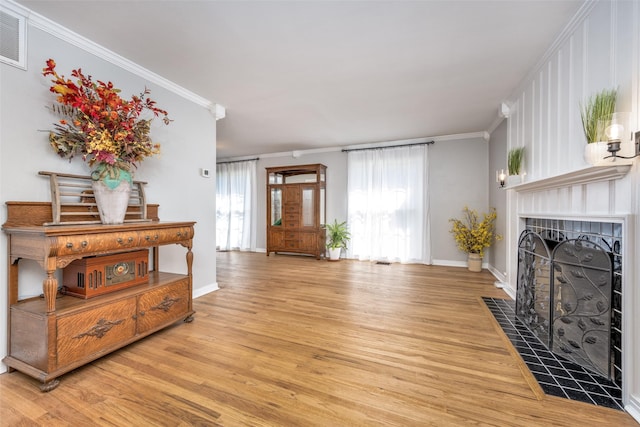 909 Coffield St, Bowie, TX 76230 - living room with crown molding, light wood-style floors, and a tile fireplace