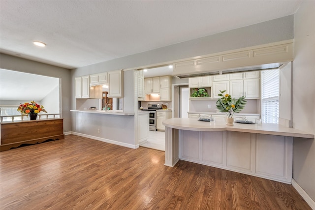 909 Coffield St, Bowie, TX 76230 - kitchen featuring stainless steel stove, a peninsula, light wood-style floors, light countertops, and white cabinetry