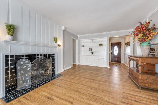 909 Coffield St, Bowie, TX 76230 - living room with a tiled fireplace, wood finished floors, built in features, crown molding, and a decorative wall