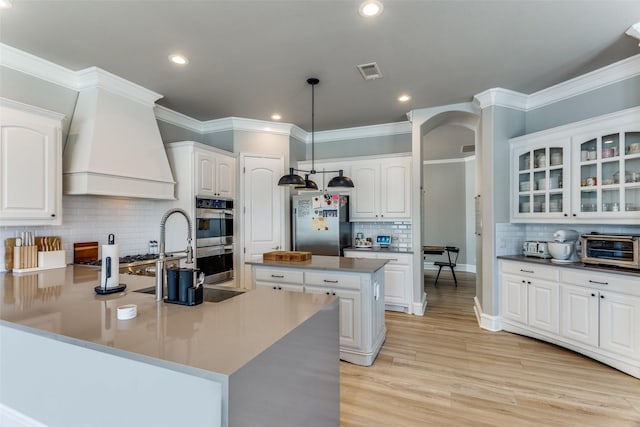 kitchen with decorative backsplash, a peninsula, glass insert cabinets, white cabinetry, and appliances with stainless steel finishes