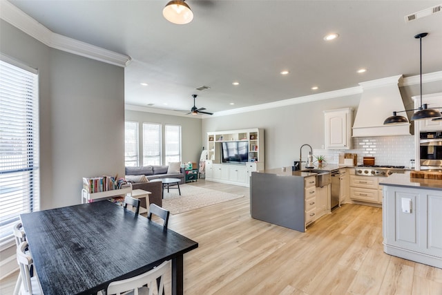 kitchen featuring visible vents, crown molding, custom range hood, a sink, and stainless steel appliances