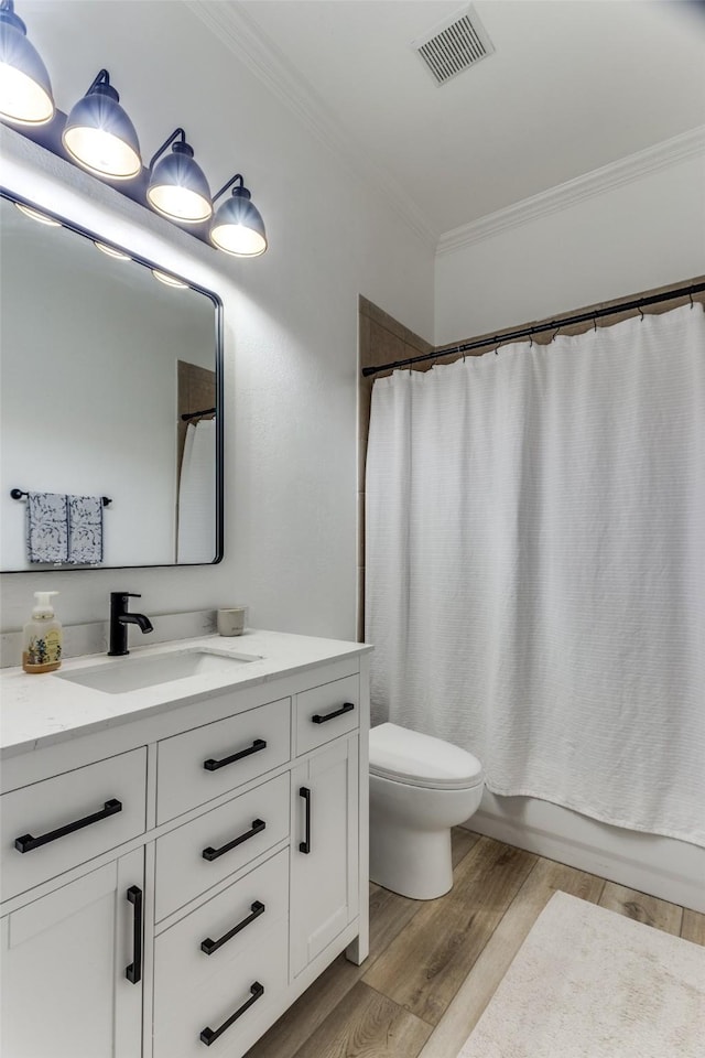 full bath featuring crown molding, visible vents, vanity, wood finished floors, and toilet