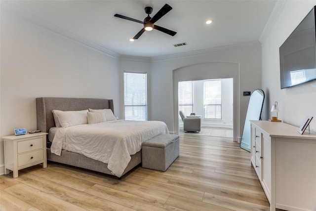 bedroom featuring visible vents, ornamental molding, light wood-style flooring, and ceiling fan