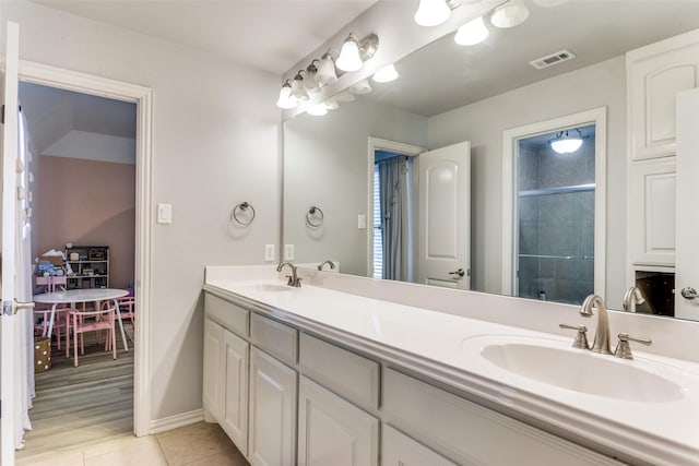 full bath with a sink, a stall shower, double vanity, and visible vents