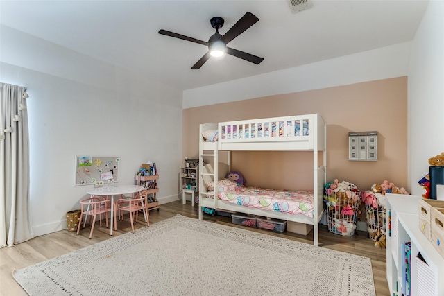 bedroom featuring visible vents, a ceiling fan, baseboards, and wood finished floors