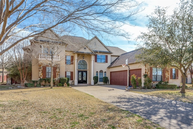 view of front of property featuring a garage, stucco siding, french doors, a shingled roof, and driveway