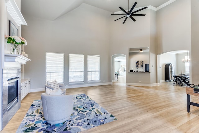 living room with arched walkways, plenty of natural light, a fireplace, and ceiling fan with notable chandelier