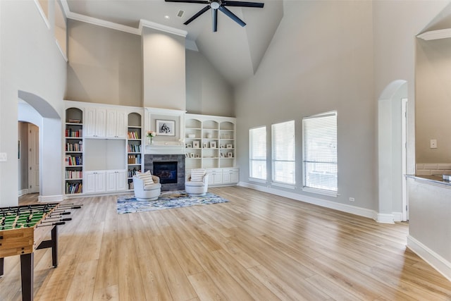 unfurnished living room with high vaulted ceiling, a ceiling fan, arched walkways, and a tile fireplace