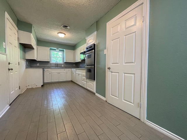 3408 Chaffin Dr, Richland Hills, TX 76118 - kitchen featuring a textured ceiling, dark wood-style flooring, a sink, double oven, and white cabinets