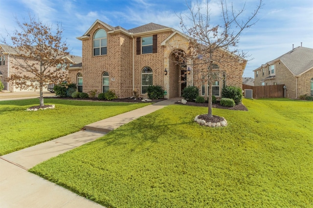 view of front facade featuring brick siding, a front lawn, and fence