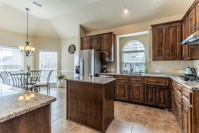 kitchen featuring light stone counters, visible vents, a sink, vaulted ceiling, and appliances with stainless steel finishes