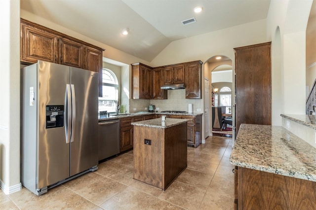 kitchen with under cabinet range hood, light stone counters, visible vents, and appliances with stainless steel finishes