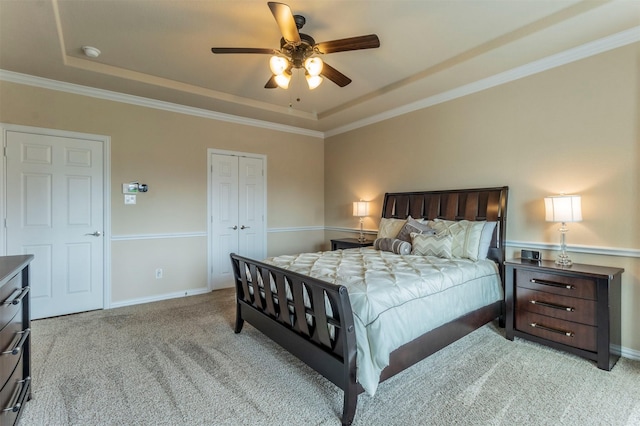 carpeted bedroom with a closet, baseboards, a raised ceiling, and ceiling fan