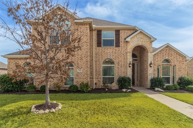 traditional home with brick siding, roof with shingles, and a front yard
