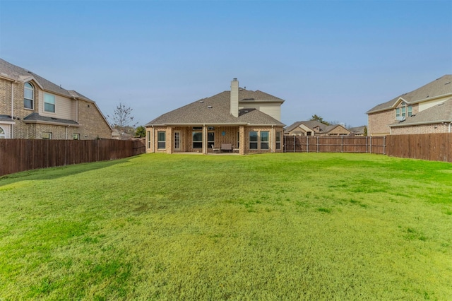 back of property with a lawn, a fenced backyard, and a chimney
