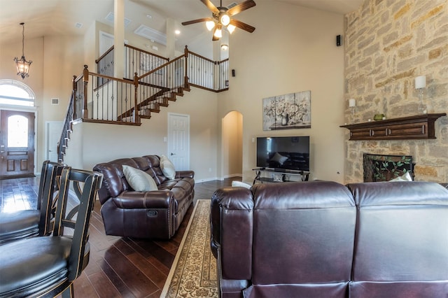 living area featuring arched walkways, stairs, a ceiling fan, and dark wood-style flooring