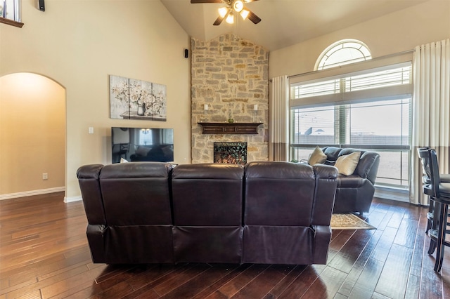 living room with arched walkways, a healthy amount of sunlight, dark wood-type flooring, and a ceiling fan