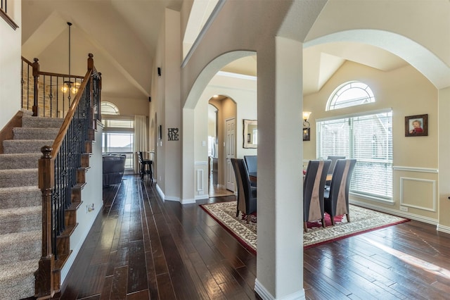 entryway featuring a wealth of natural light, stairway, dark wood-type flooring, and a towering ceiling