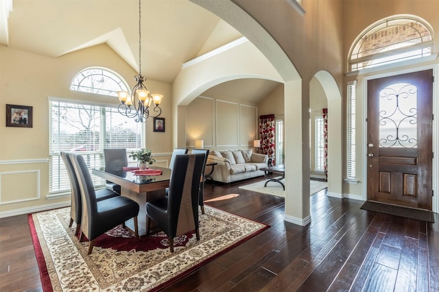 dining room with dark wood-style floors, a decorative wall, high vaulted ceiling, and a chandelier