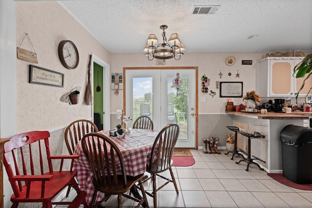 dining area with a chandelier, a textured ceiling, light tile patterned floors, and visible vents