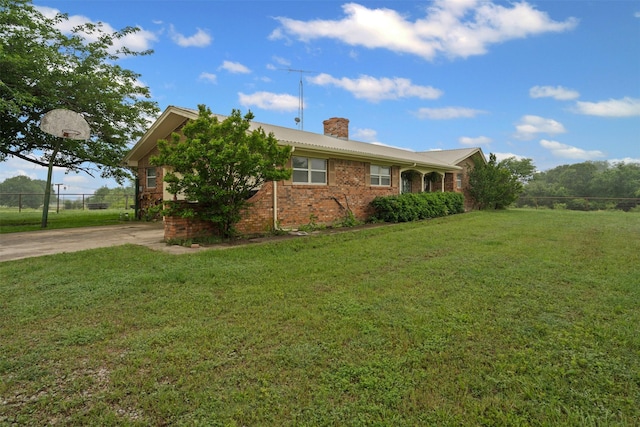 view of front of property with brick siding, fence, a chimney, and a front yard