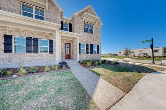 traditional home with a front yard and brick siding