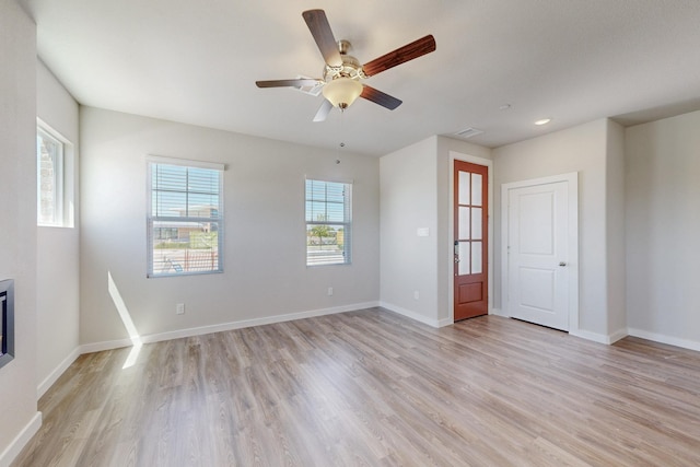 empty room with light wood-style floors, a ceiling fan, visible vents, and baseboards
