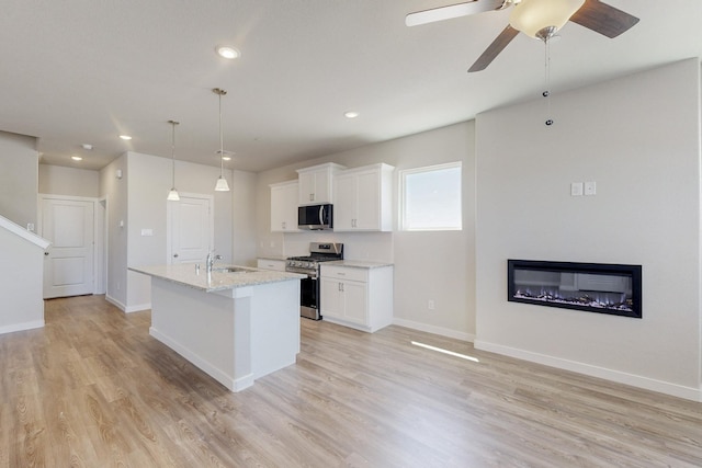 kitchen with appliances with stainless steel finishes, white cabinetry, a kitchen island with sink, and a sink
